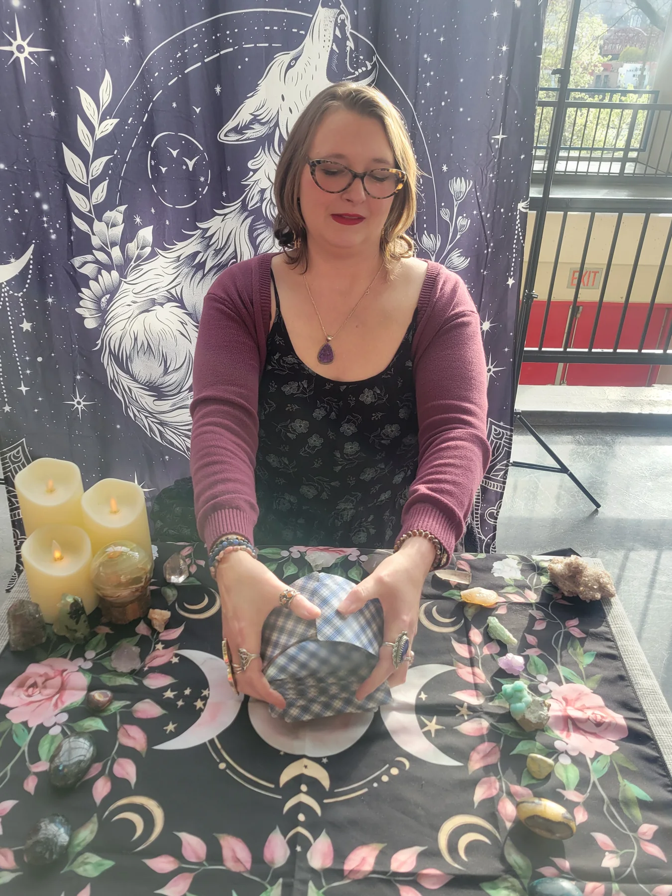 Crystal shuffling her plaid-backed tarot deck over a floral moon cloth.
