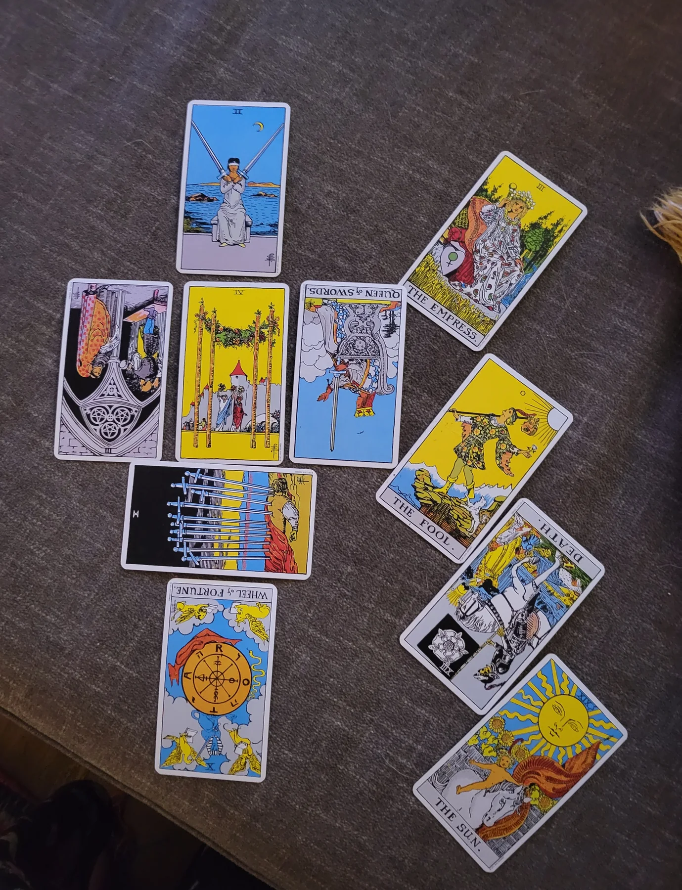 Ten tarot cards arranged in a spread on a gray couch.